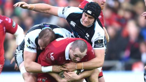 James King and Alun Wyn Jones tackling Ken Owens in October 2017 during a Welsh derby between Ospreys and Scarlets