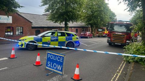 A police car and a fire engine behind a police cordon