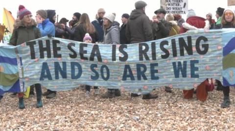 Protesters hold a banner saying: "The sea is rising and so are we."