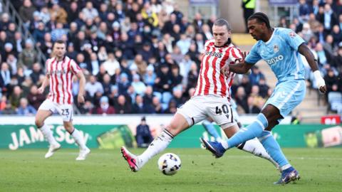 Coventry City's Haji Wright takes a shot as Stoke City's Maksym Talovierov tries to block.