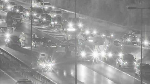 A night-time CCTV image of cars queuing at junction five of the M40. There are cars pulled over and people standing in the slip road off the motorway.