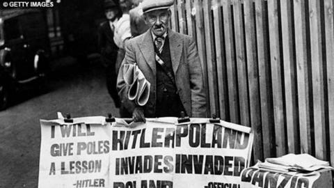 Newspaper seller, with headlines in hand, carrying the news that the Nazis had invaded Poland