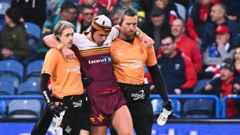 George Flanagan is helped from the field having been injured in Huddersfield's loss to Hull KR on Sunday
