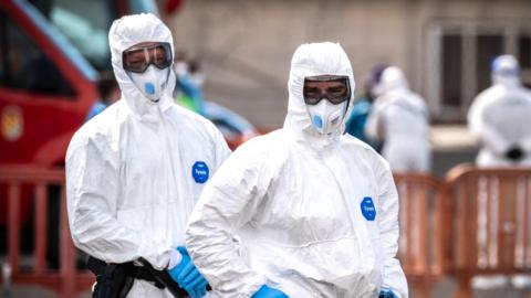Two people in white suits and masks