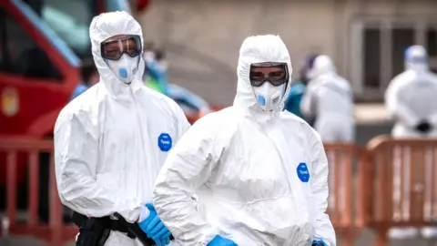 Two people in white suits and masks