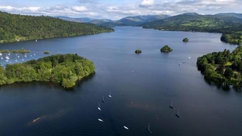 An aerial view of Windermere. It's a clear day and boats are sailing on the lake. 