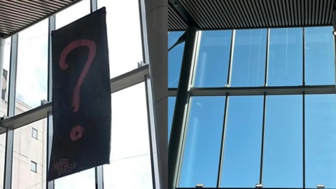 To the left is an image of a black banner with a large pink question mark on it hanging from a ceiling. To the right is an image of the same space without the question mark. 