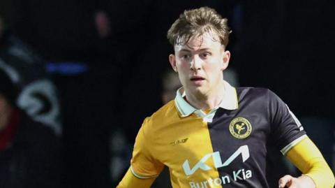 JJ McKiernan playing for Burton Albion in a gold and black shirt