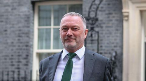 Steve Reed, secretary of state for housing, communities and local government, outside No 10. He is wearing a grey suit with a green tie.
