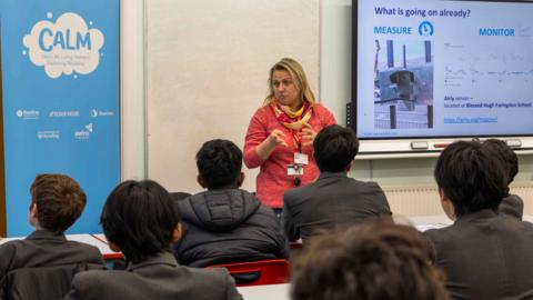 Teacher in a classroom delivering a lesson on air quality control.