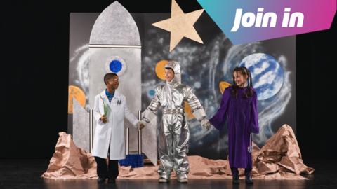 A school stage with pupils dressed as astronauts and scientists. 