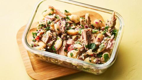 A glass container of butter bean, tuna and parsley salad.