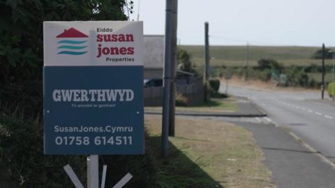 Arwydd 'Gwerthwyd' tu allan i eiddo ym Morfa Nefyn