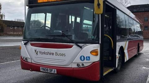 A parked bus owned by firm Yorkshire Buses in a red and white livery.