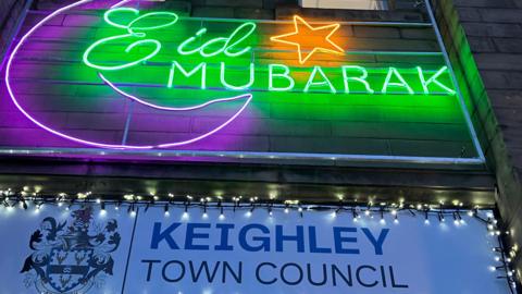 Eid Mubarak written in green neon lights with a white sign underneath that says Keighley Town Council