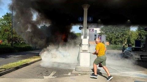  a man with a fire extinguisher running towards the Pontiac Firebird which is on fire. There is a lot of smoke.