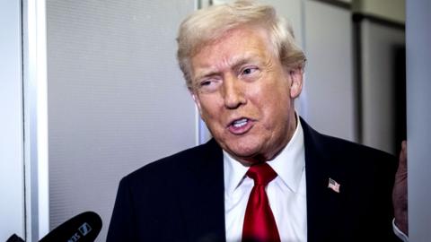 US President Donald Trump speaks to reporters on board Air Force One