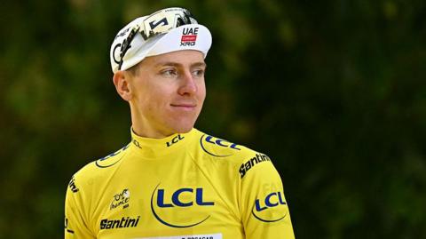 Tadej Pogacar wearing a yellow jersey and white hat