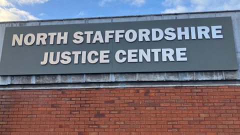 A large grey sign at the top of a red brick wall reads North Staffordshire Justice Centre