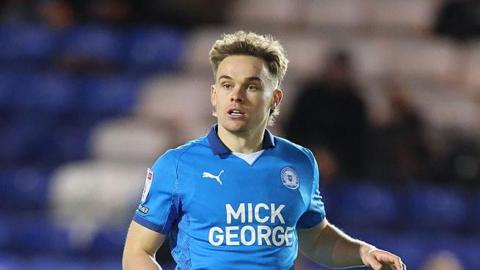 Midfielder Archie Collins playing in the blue shirt of Peterborough