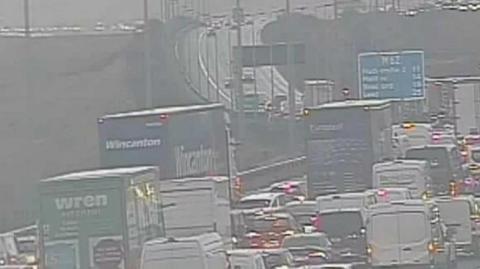 Congestion on M62 with lots of lorries, vans and cars seen amid much spray on a very wet morning