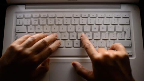 Hands on a laptop keyboard.