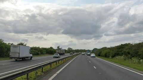 View of part of the A14. It is a dual carriageway road and cars and lorries are driving along both sides.