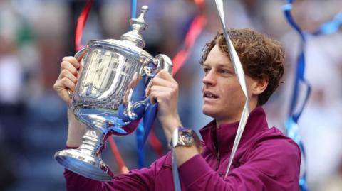 Jannik Sinner of Italy celebrates with the winner's trophy after defeating Taylor Fritz