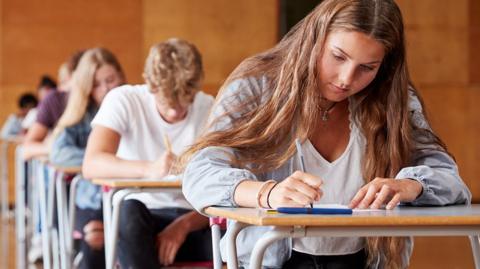 GCSE Physics image: an exam hall with teenage students taking exams, concentrating.