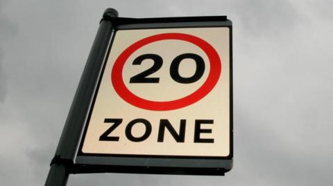 Close-up image of a 20mph zone sign, against a cloudy background.