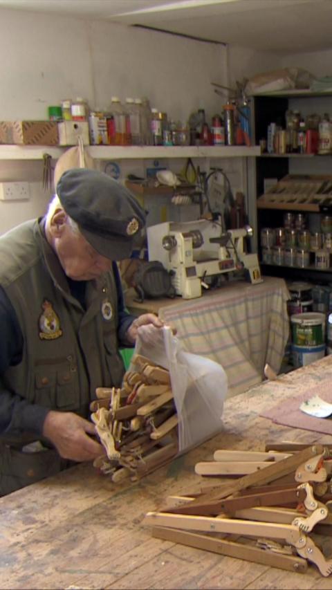 Man wearing Army gear at a workshop with lots of wood in front of him.