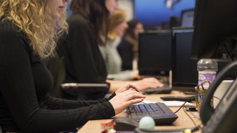 Office workers at their desks typing on keyboards.