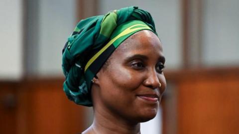 Duduzile Zuma-Sambudla is seen in a black dress and a green and yellow scarf wrapped around her head