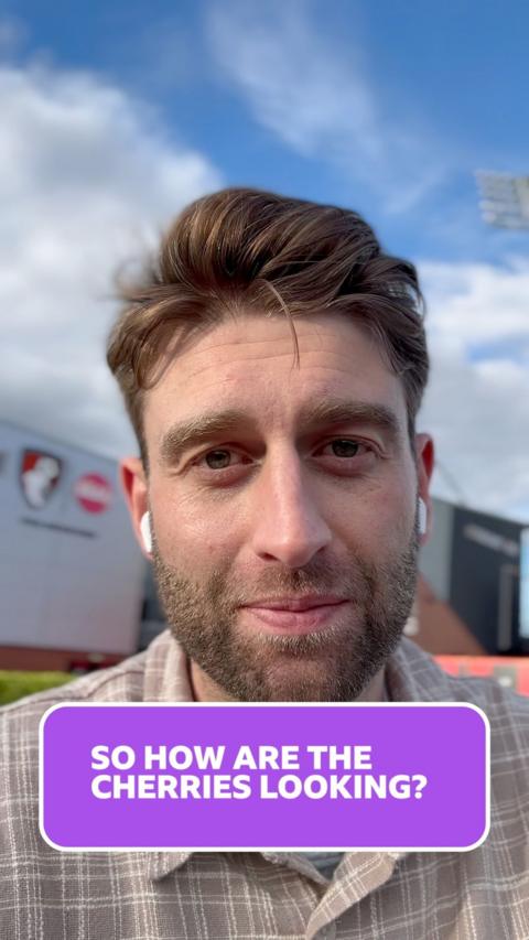 Jordan Clark stands outside the AFC Bournemouth stadium, looking at the camera. He has dark blonde hair and a short beard and wears a beige and white check shirt.