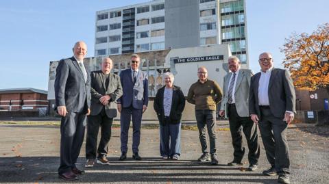 Members of the Thornaby Town Deal Board stand in front of the Golden Eagle. From left, they are Andy McDonald, MP for Middlesbrough and Thornaby East, Steve Walmsley, Mark White CBE DL, Councillor Sylvia Walmsley, Councillor Ray Godwin, Councillor Ian Dalgarno and Councillor Nigel Cooke. Much of the Golden Eagle building is boarded up.