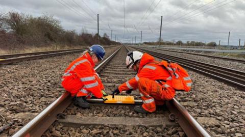 Two people working in the middle of a railway track.