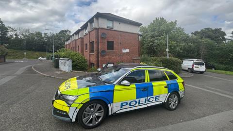 A police car parked outside an apartment block. 
