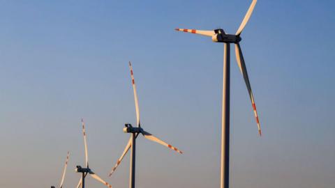 Four wind turbines in a row against blue-red sky