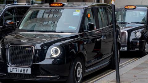 A row of black cabs parked in a town centre
