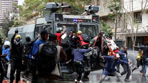 Protesters in front of a police vehicle