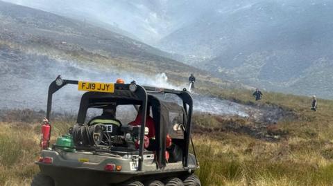 Fire vehicle and firefighters tackle fire at Tintwistle Moor