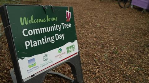 A sign which reads 'welcome to our community tree planting day' 