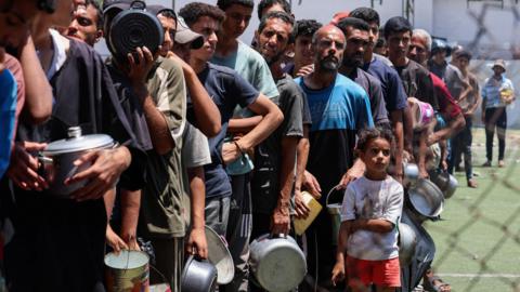 Palestinians gather to receive food from a charity kitchen in Gaza on 20 July