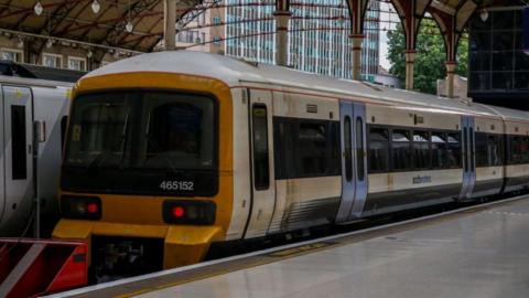 A white Southeastern Class 465 train, with a yellow front and blue doors, at London Victoria station