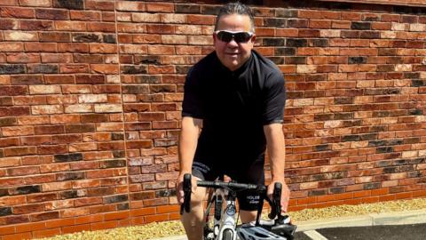 Adrian Heeley posing on his bike against a brick wall