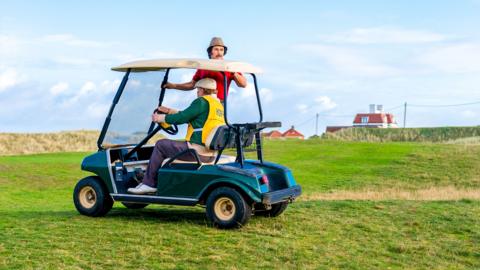 Two men riding in a golf cart
