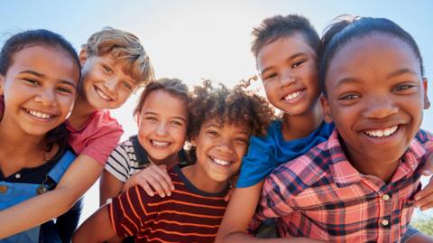 a group of six children looking at the camera and smiling.