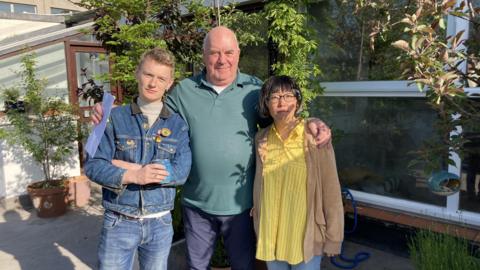 Three residents in front of a small garden