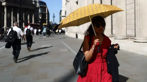 A person with an umbrella shields themself from the sun while walking through central London on Tuesday