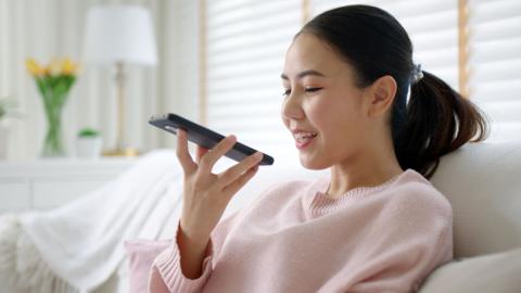 Woman looking at her phone and speaking into it. 